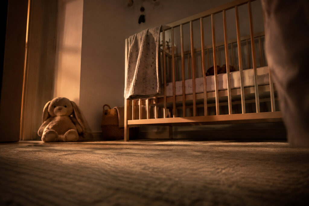 Lit de bébé en bois avec une peluche lapin, baigné dans une lumière douce et tamisée en soirée.